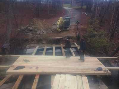 Owl Brook Bridge - workers laying timber deck planking with excavator in background