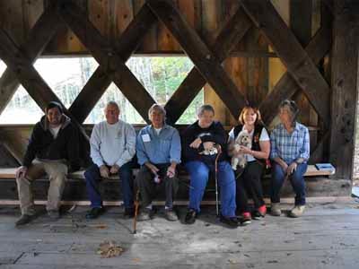 Group of six people seated inside Ashokan covered bridge