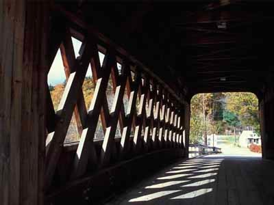 Squam River covered bridge interior looking through with lattice truss shadows in autumn light