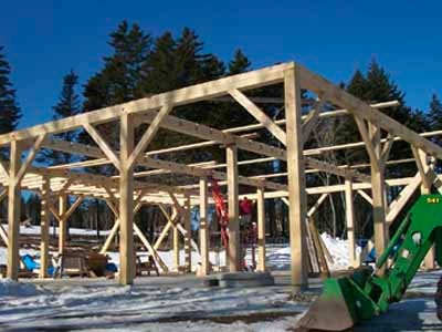 Garner timber frame under construction in winter with John Deere loader in foreground