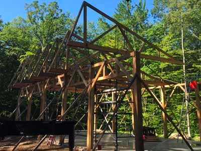 Holderness barn timber frame raising with gin poles and scaffolding in summer